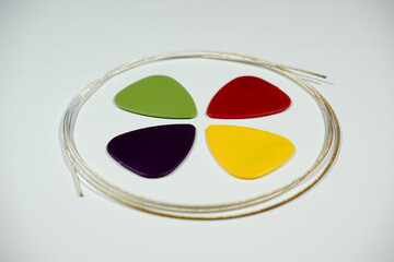 multicolored picks and a guitar string on a white background