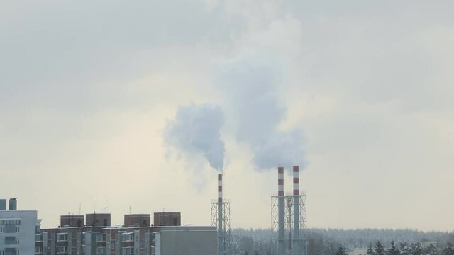 Smoke slowly rises from the chimney of the boiler room in winter.