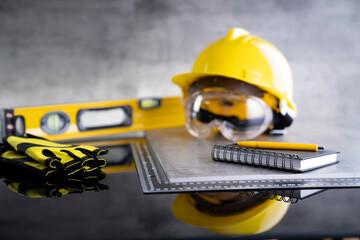 Contractor concept. Tool kit of the contractor: yellow hardhat, libella and tools on the gray background.