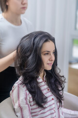 Obraz premium Dark-haired young woman making hairstyling in a hair salon