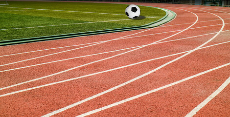 Obraz premium Soccer ball black and white classic with lines on green artificial grass at public outdoor football stadium with runing track field, sport,