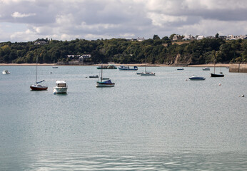 Obraz premium Fishing boats and yachts moored in the bay at high tide in Cancale, famous oysters production town. Brittany, France,