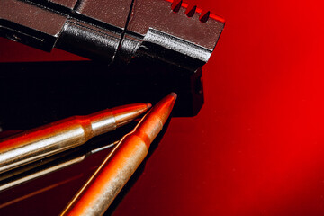 Black gun and cartridges on background with red reflection