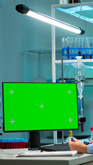 Doctor talking with lab technician and working with green mock-up screen desktop computer. Man lab researcher discussing with doctor about vaccine developent looking at blood samples