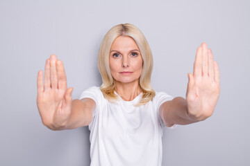 Photo portrait of serious old woman showing two palms signaling to stop isolated on grey colored...