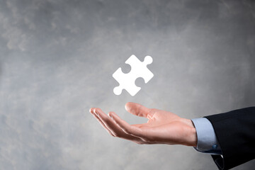 Businessman hands connecting puzzle pieces representing the merging of two companies or joint...