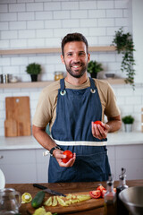 Portrait of handsome man cutting vegetables. Young man preparing salad.