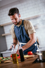 Portrait of handsome man cutting vegetables. Young man preparing salad.