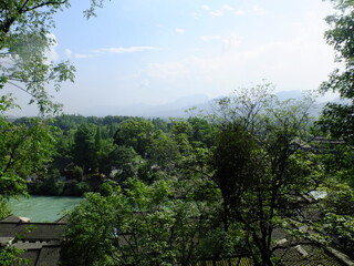 Min river flowing past traditional houses and a rich green landscape in Dujiangyan, Sichuan, China