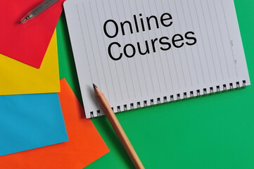 Education concept in reference to online learning. Notebook, pencils, pen, colored papers with text 'Online Courses'.  Selective focus points