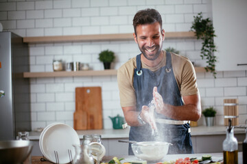 Happy man baking in the kitchen. Man making delicious food at home..