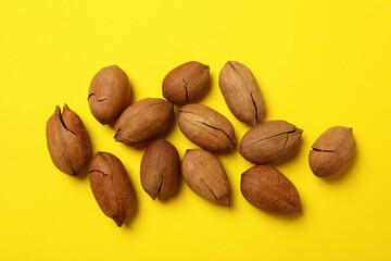 Tasty pecan nuts on yellow background, top view