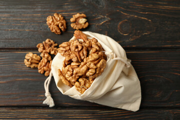 Cotton bag with tasty walnuts on wooden background