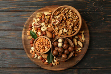 Tray with bowls with different nuts on wooden background