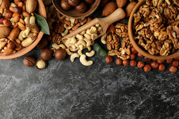 Bowl and wooden scoop with different nuts on black smokey background