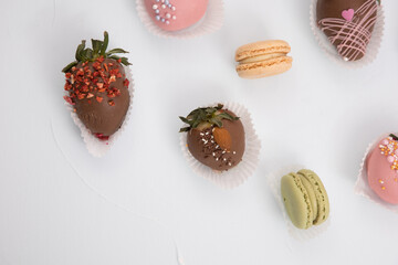 Assorted strawberries in chocolate with macaron, sweet dessert, free space for your text, sprinkled with nuts, top view, isolated background.