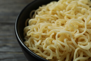 Bowl with cooked noodles on wooden background, close up