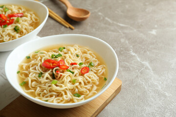 Concept of tasty eating with bowls of noodles on gray background