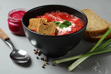 Concept of tasty eating with borscht and ingredients on gray table