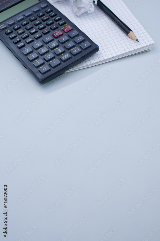 Poster vert shot of a calculator, a notepad and a pencil isolated on gray background