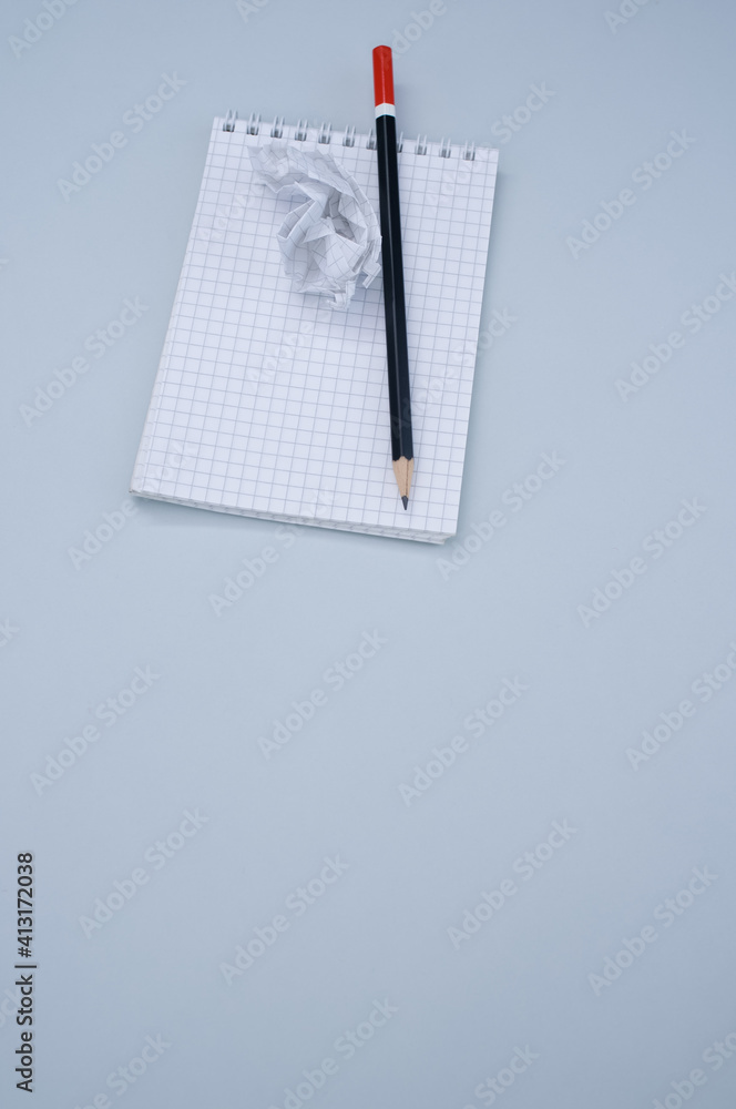 Poster vertical top view of a notepad, pencil and a crumpled sheet of paper isolated on gray background