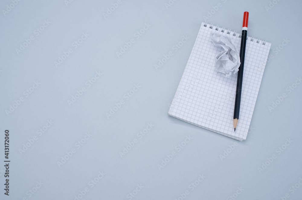 Poster top view of a notepad, pencil and a crumpled sheet of paper isolated on gray background