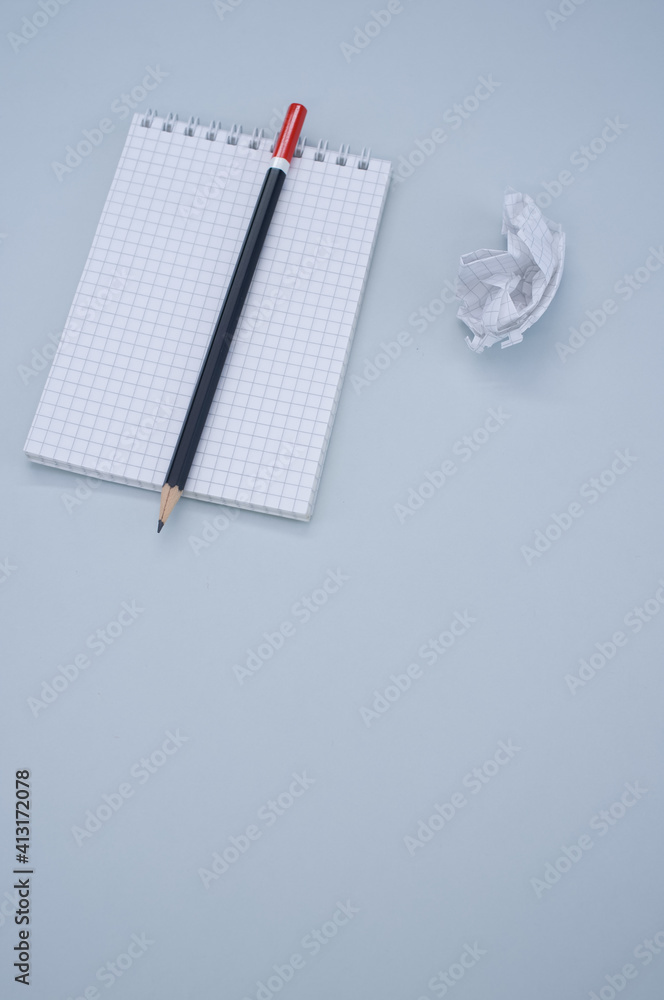 Poster vertical top view of a notepad, pencil and a crumpled sheet of paper isolated on gray background