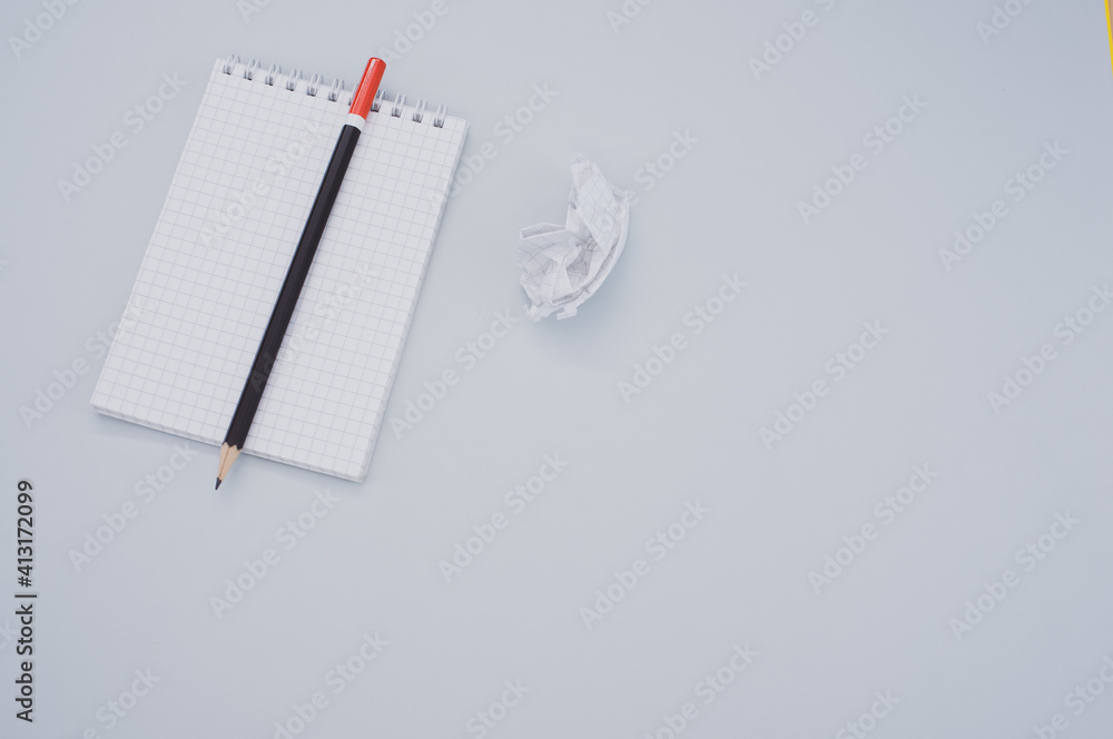 Poster top view of a notepad, pencil and a crumpled sheet of paper isolated on gray background