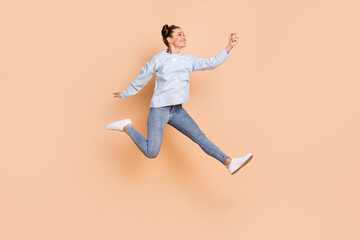 Fototapeta na wymiar Full size profile photo of optimistic nice brunette lady jump catch wear blue sweater jeans sneakers isolated on beige background