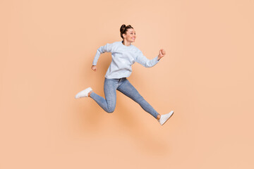 Fototapeta na wymiar Full size profile photo of optimistic nice brunette lady jump run wear blue sweater jeans sneakers isolated on beige background