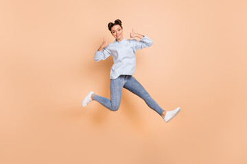 Fototapeta na wymiar Full size profile photo of optimistic nice brunette lady jump show ok wear blue sweater jeans sneakers isolated on beige background