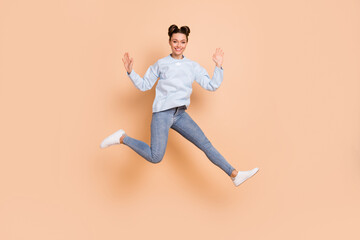 Fototapeta na wymiar Full size profile photo of optimistic nice brunette lady jump run arms up wear blue sweater jeans sneakers isolated on beige background