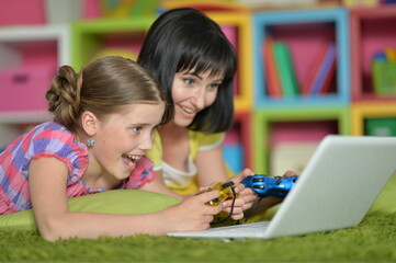 portrait of smiling   mother and daughter using laptop playing video game