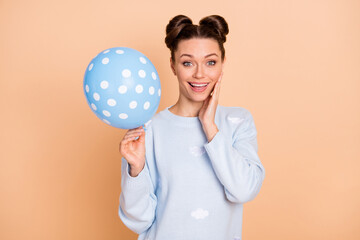 Photo of impressed nice brunette lady hold balloon wear blue sweater isolated on pastel beige color background