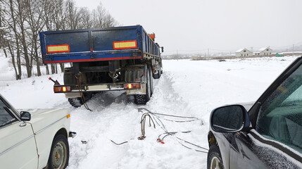 a large car pulls two small ones out of the snow captivity