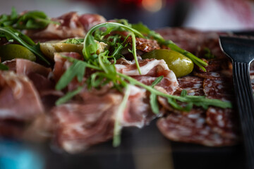 Close-up of basturma sliced into pieces. Dried meat with spices cut into slices. Dried horse meat on a wooden board with rosemary and caraway herbs.