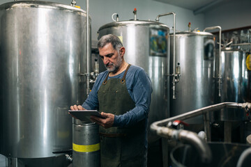 brewer working on digital tablet in his craft beer brewery