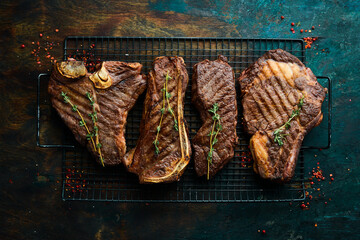 Set steaks on the grill: t-bone, striploin, Rib eye, new york steak. Top view. Rustic style.