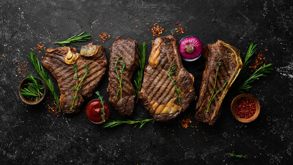 Steak menu. Juicy grilled steaks on a black stone background: t-bone, striploin, Rib eye, new york steak. Top view. Rustic style.