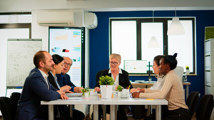 Business team starting morning with brainstorming meeting coming in broadroom discussing company problems. Executive director briefing multiethnical people, explaining start up financial reports