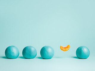 Creative pattern made of outstanding levitating orange slice surrounded by blue colored oranges on blue background. Fruit minimal concept. Gradient colors palette. Top view, flat lay, close up.