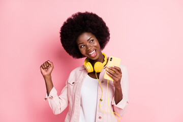 Portrait of pretty cheerful girl using device listening pop single enjoying free time dancing isolated over pink color background