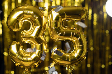 The golden number 35 thirty five is made from an inflatable balloon on a yellow background. One of the complete set of numbers. Birthday, anniversary, date concept