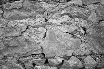evocative black and white image of texture of old stone wall 
