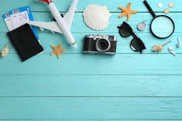 Flat lay composition with toy airplane and travel items on light blue wooden background. Space for text