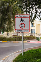 Slow down in school zone warning sing for motorist, yellow school bus and road signal. School buses lined up during foggy weather at United Arab Emirates