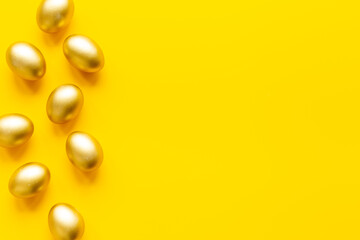 Golden eggs on yellow. Easter decoration background. Top view