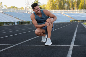 Man in sportswear having knee problems at stadium