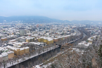 Fototapeta premium Cityscape of Graz with Mur river and historic buildings rooftops in winter with snow, in Graz, Styria region, Austria