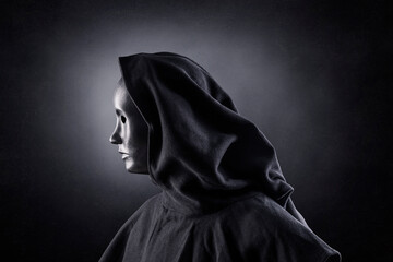 Scary figure with hooded cloak in the dark